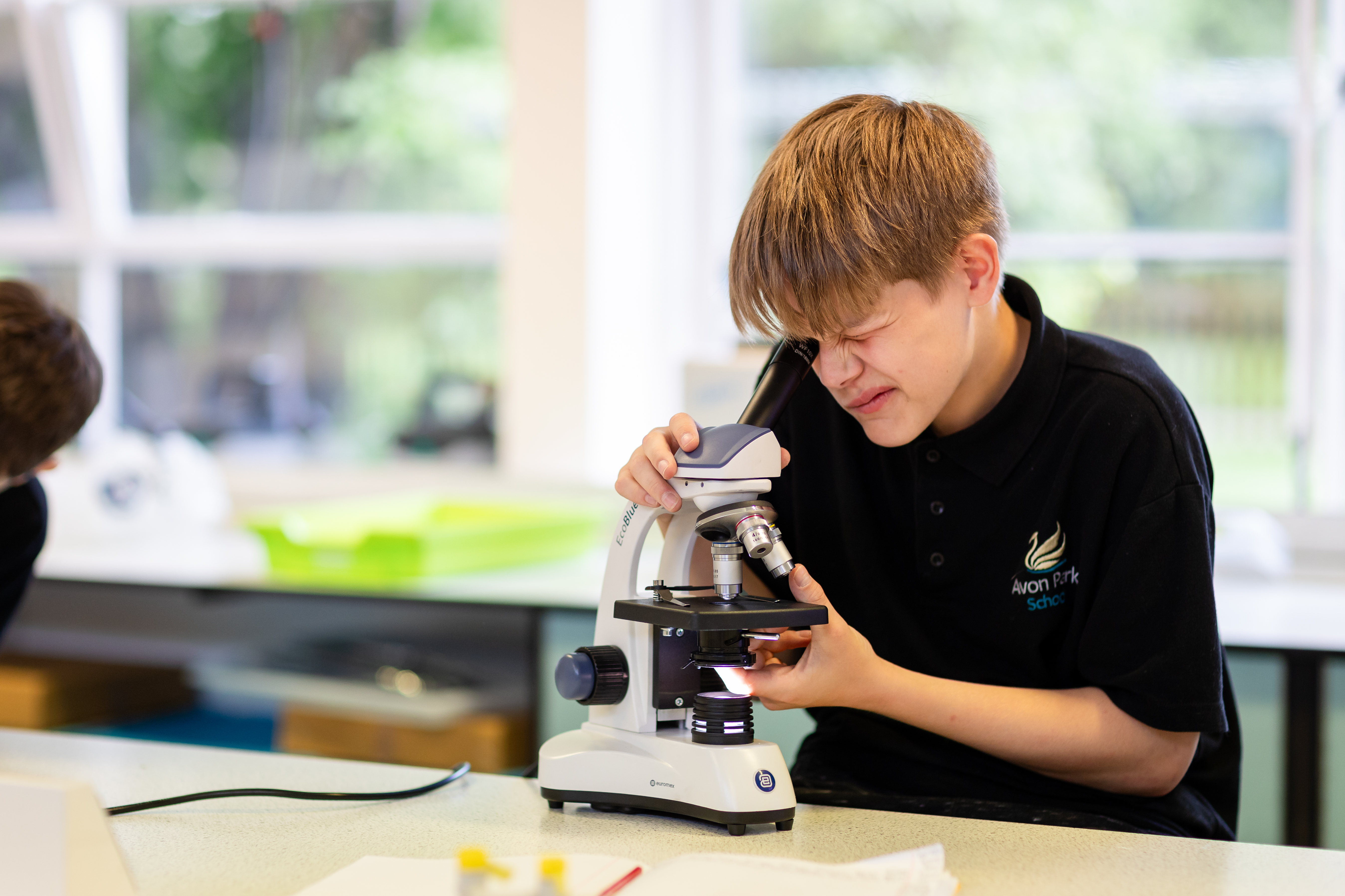 A young boy looking through a microscope in a lab at Avon Park School